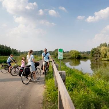 gezin op de fiets aan het water naast een knooppuntbord