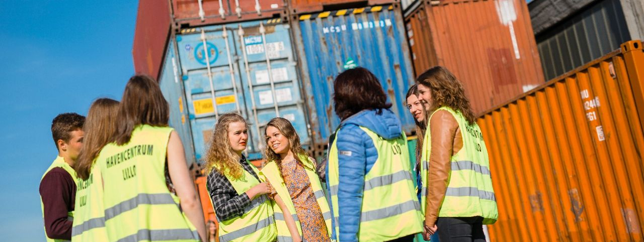 Leerlingen krijgen uitleg van een gids over containers in de haven (bedrijfsbezoek aan een containerterminal)